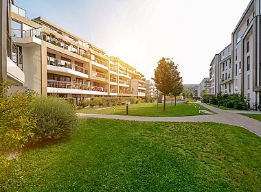 Grüner Garten zwischen verschiedenen Mehrfamilienhäusern