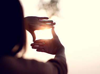 Frau schaut durch ihre zum Quadrat geformten Hände auf den Horizont