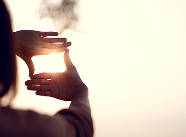 Frau schaut durch ihre zum Quadrat geformten Hände auf den Horizont