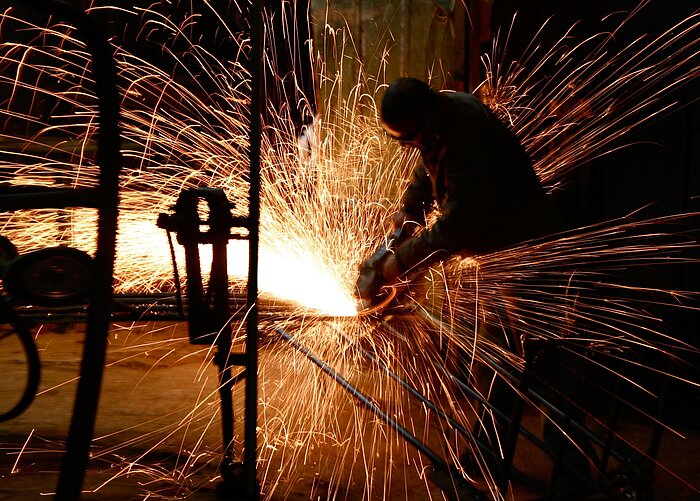 Arbeiter flext Stahl in einer Industriehalle