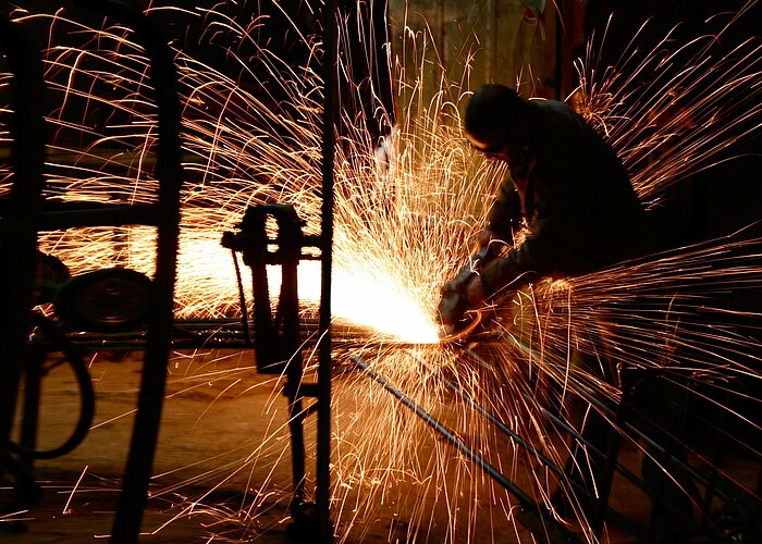 Arbeiter flext Stahl in einer Industriehalle