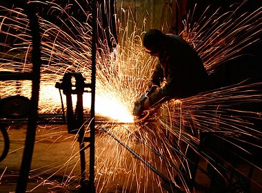 Arbeiter flext Stahl in einer Industriehalle